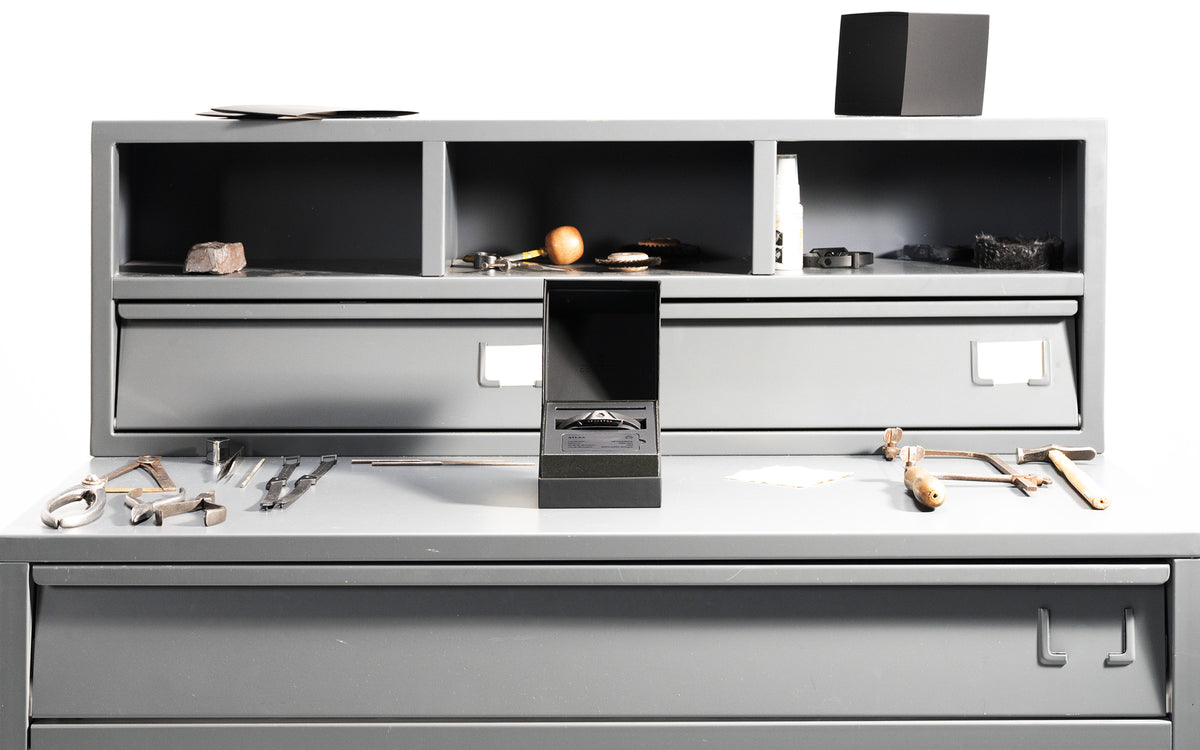 Boite contenant un braclet atlas spacefox posé sur une table d'artisan avec des outils autour
